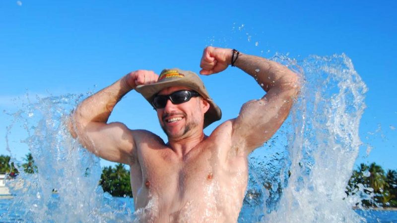 man flexing his muscles in the water